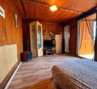 Wooden interior with a bed and a wardrobe, marked with the real estate agency's logo.