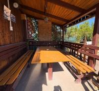 A wooden gazebo with a table and benches in the garden of Komárno, ideal for relaxation.