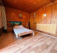 A wooden interior with a patterned bed and paintings on the walls.