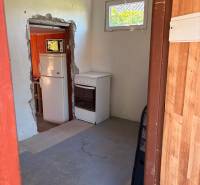 Interior with a stove and refrigerator, view into the garden through a small window.
