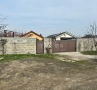 In Zálesí on Domky Street, there is a closed gate and a concrete fence surrounding agricultural and forest land.