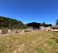 A garden with cultivation beds and a wooden shelter by a family house in Slovenská Kajňa.