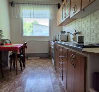 A kitchen in a family house with a wooden kitchen unit and a window that lets in daylight.