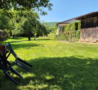 The garden of a family house in Slovenská Kajňa with plastic chairs and a wooden shelter.