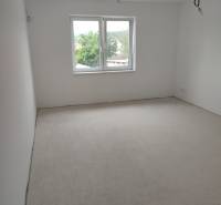 A spacious, bright room in a family house, white walls and a large window.
