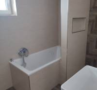 A bathroom in a family house with a bathtub, a sink, and tiles on the walls and floor.