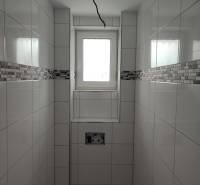 A bathroom in a family house with tiles and a window, without sanitary equipment.