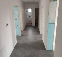 Hallway in a family house with tiles, white walls, and entrances to rooms.