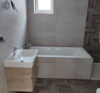 Bathroom in a family house with a bathtub, sink, and ceramic tiles.