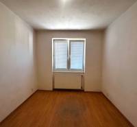 An empty room with a parquet floor and a window in a 3-room apartment.