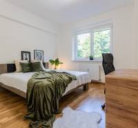 Bedroom in a 3-room apartment with a bed, wooden floor, and a desk.