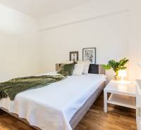 A bright bedroom with a large bed and a green throw in a 3-room apartment.