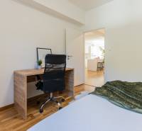 A workspace with a wooden desk and a black chair in a 3-room apartment.