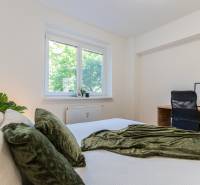 A bright bedroom with a bed and a desk in a 3-room apartment.