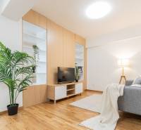 Living room with wooden flooring, gray sofa, dresser, and houseplant in a three-room apartment.