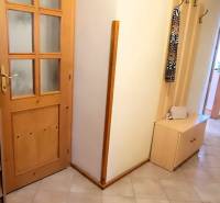 A hallway in a 3-room apartment with wooden furniture and decoration in a vase.
