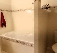 A bathroom with a bathtub and a sink in a 3-room apartment, light tiles, red towel.