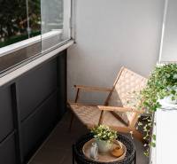 Balcony of a 2-room apartment with a chair, table, and plants.
