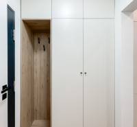 White built-in wardrobe with wooden detail and hooks in a 2-room apartment.