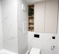 A minimalist bathroom in a 2-room apartment with a toilet, bathtub, and storage spaces.