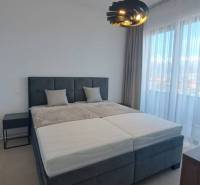 Bedroom with a large bed and a modern lamp in a two-room apartment.