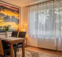 Living room in a studio apartment with a wooden table and picture decor on the wall.
