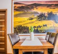 Dining table with a vase of tulips, large landscape photograph on the wall.
