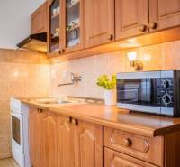 A kitchenette in a studio apartment with a microwave and wooden cabinets.