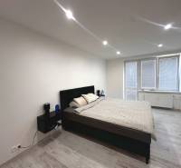 Bedroom in a two-room apartment, with a bed and nightstands, light flooring.