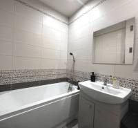 Bathroom in a 2-room apartment with a bathtub, sink, and mirror on the wall.