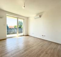 Living room with wooden flooring, balcony doors, and air conditioning in a 2-room apartment.
