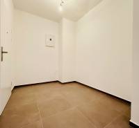 A hallway with light walls and brown tiles in a 2-room apartment.