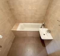 A bathroom in a 2-room apartment with a bathtub and a sink, light tiles.