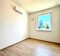 A bright room with wooden flooring, a window, and air conditioning in a 2-room apartment.