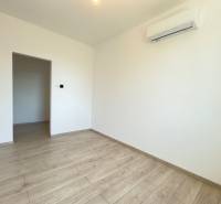 An empty room in a 2-room apartment with white walls and laminate flooring.
