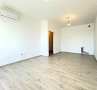 A room in a two-room apartment with air conditioning and wooden flooring, bright walls.
