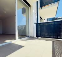 A balcony of a 2-room apartment with sliding doors and a view of the surrounding architecture.