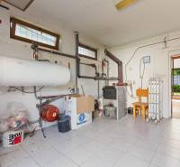 Gas boiler with piping and wooden furniture in the interior of the cabin.