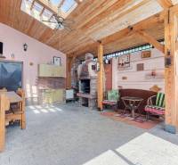A wooden gazebo at the cottage in Kuchyňa with a fireplace, table, and benches.