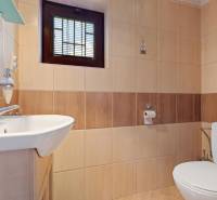 A bathroom in a cabin with a sink, toilet, and ceramic tiles in warm shades.