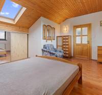 A bedroom in a cottage with wooden furniture, a skylight, and a cabinet.