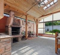 Covered terrace at the cottage in Kuchyňa with a brick grill and wooden furniture.