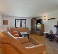 Living room of the cottage with a leather sofa, fireplace, and wooden furniture.