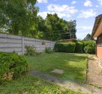A garden at the cottage in Kuchyňa with a lawn, a wall, and lush greenery.