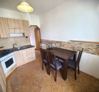 A kitchen in a 3-room apartment with light wooden furniture and a dining table.