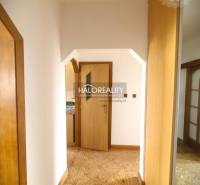 A hallway in a 3-room apartment with light wood paneling and parquet flooring.