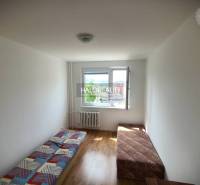A simple room with two beds in a 3-room apartment, laminate flooring, bright atmosphere.