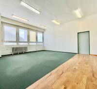Office interior with windows, parquet floors, and carpets, suitable for a work environment.