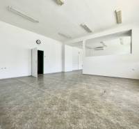 Spacious offices with white walls, tiled floor, doors, clock on the wall.