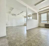 Offices with empty space, white walls, large windows, and a radiator.